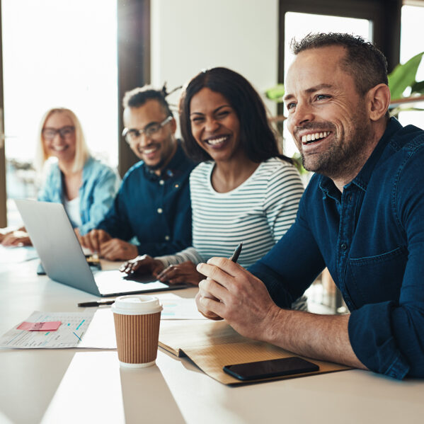Diverse,Group,Of,Young,Businesspeople,Laughing,While,Sitting,Together,In